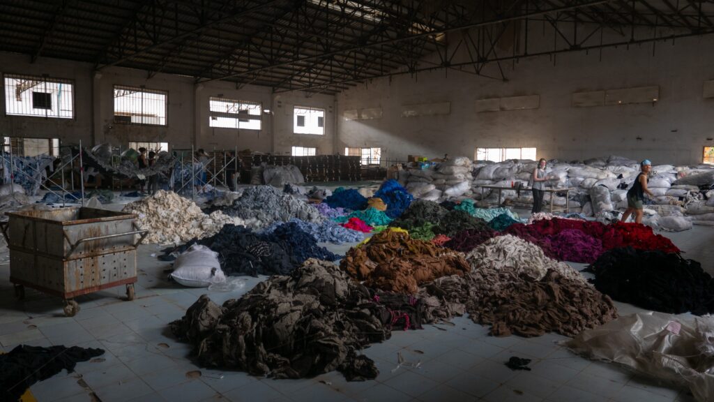 Sorting through hundreds of tons of clothing in an abandoned factory for a social mission called Clothing the Loop. Photo by Francois Le Nguyen on Unsplash